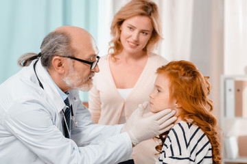 selective focus of doctor in medical gloves examining little patients throat in clinic