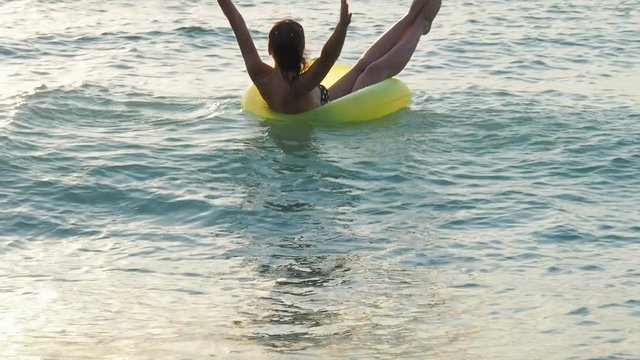 A happy girl on an inflatable circle is floating on the waves.