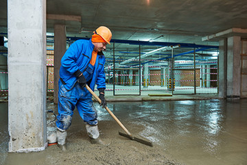 concrete floor construction. Worker with screeder
