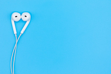Top view of White Earphones on Blue plastic texture background. Pastel color concept, Minimal concept. Copy space. Music is my life concept