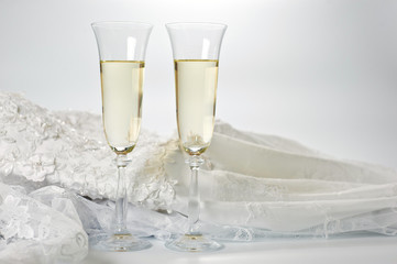 Glasses with champagne and wedding dress on a white background