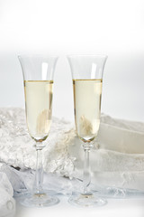 Glasses with champagne and wedding dress on a white background