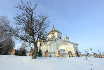 Christmas winter landscape with white Church and a tree