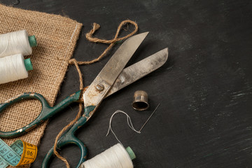 Retro sewing accessories on black wooden background