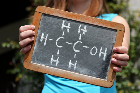 chemical formula for ethanol written with chalk on slate shown by young female