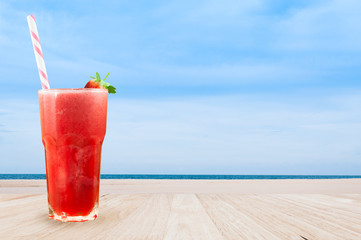 Strawberry juice smoothie in glass with fresh strawberry on table wooden with beach landscape view...
