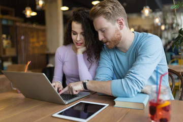 Happy couple spending time at coffee shop working on laptop