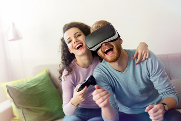 Happy young couple playing video games with virtual reality headsets