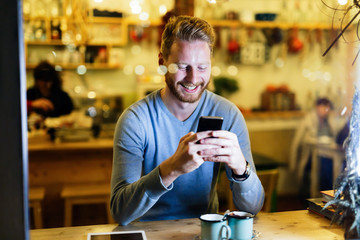 Handsome man using mobile phone in coffee shop