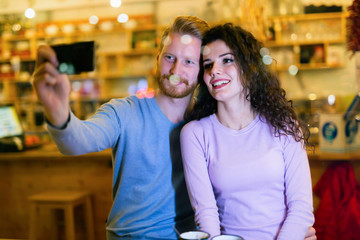 Happy couple taking selfie in coffee shop