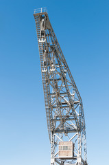 Fototapeta na wymiar metal port crane with three hooks and blue sky