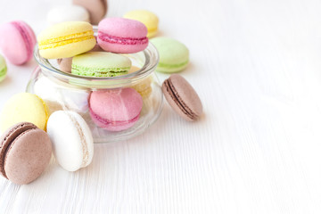 Different macaroons in a glass vase on a table
