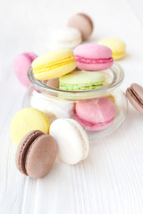 Different macaroons in a glass vase on a wooden table