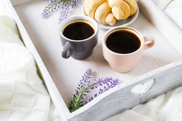 two cups of coffee with croissants on a tray