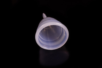White menstrual cup isolated on a black background