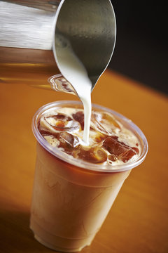 Pouring milk in iced caramel latte 