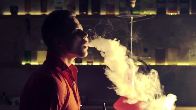 Young man smoking hookah in a bar