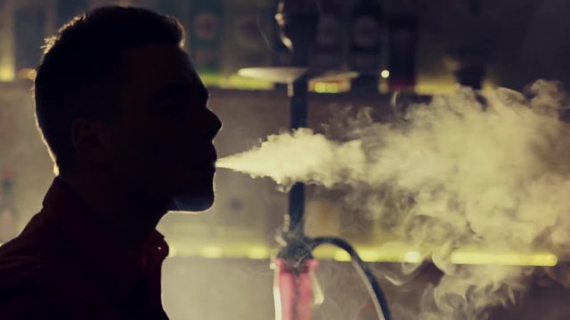 Young man smoking hookah in a bar