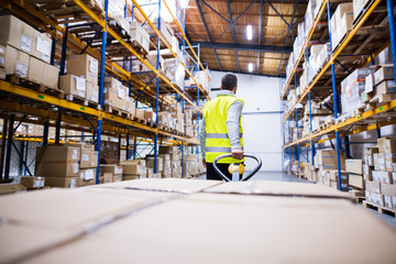 Male warehouse worker pulling a pallet truck.