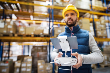 Man with tablet and drone controller in a warehouse.