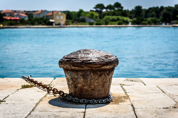 Naklejka premium Old rusty steel mooring bollard pole on a pier.