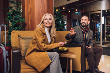 smiling mid adult couple looking away while sitting on hotel hallway