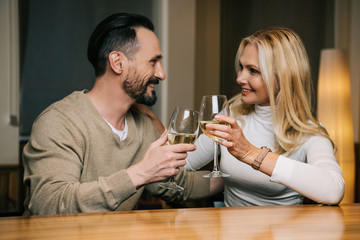 happy mature couple drinking wine and smiling each other in hotel restaurant