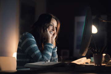 Happy woman working with her computer at night