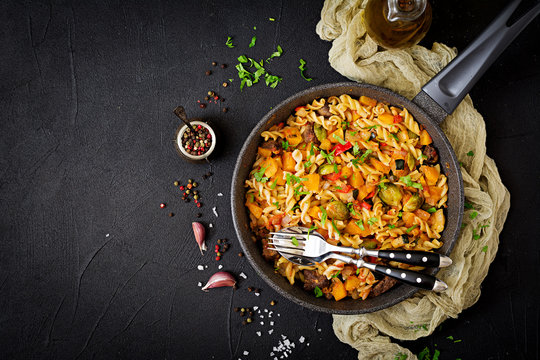 Fusilli vegetable paste with pumpkin, Brussels sprouts, paprika and liver pieces on a dark background. View from above