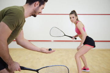 Athletic couple playing squash together .