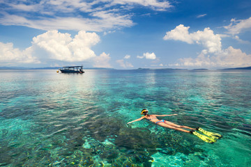 Woman snorkeling in clear tropical waters on a background of islands - obrazy, fototapety, plakaty