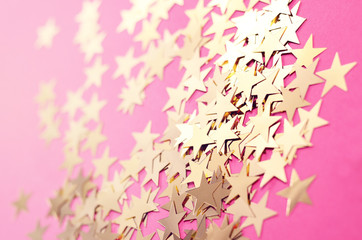 New Year background with sparkling decorative gold stars on a pink background