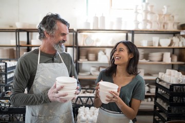 Male and female potter holding ceramic bowls