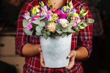 female hands holding a floral bouquet in a bucket