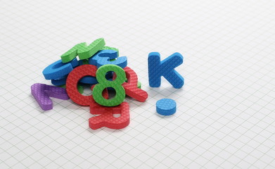 Alphabet letters and numbers pile isolated on white checkered background