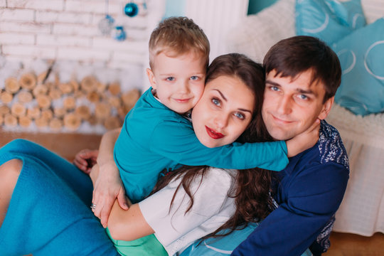 New Year's picture of happy family on background of Christmas decorations. Young parents with their son having fun and smiling on background of Christmas decorations