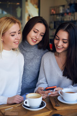Woman showing something on smartphone to two friends