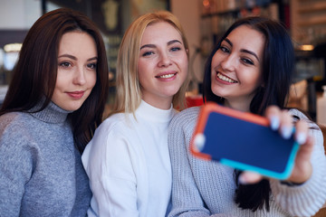 Three women making selfie at cafe