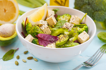 Healthy green salad with tofu, broccoli, avocado, peas and chia seeds.