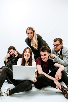 Promising young colleagues with laptop sitting on white background