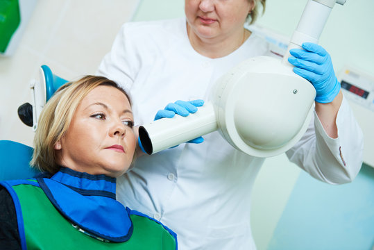dentist operates dental intraoral x-ray unit for tooth image with patient