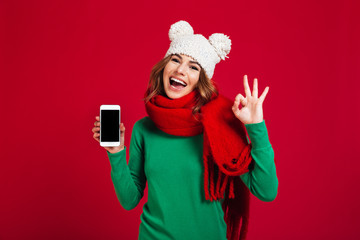 Excited pretty young woman showing display of phone