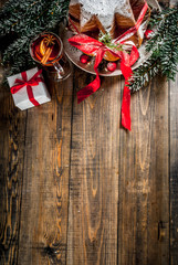 Traditional Italian Christmas fruit cake Panettone Pandoro with festive red ribbon and Christmas decorations, gift box and mulled wine, on wooden home background, copy space top view