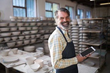 Portrait of male potter using digital tablet
