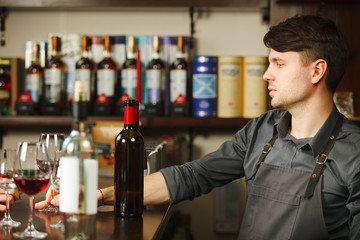 Male sommelier at bar counter closeup of alcohol drinks bottles
