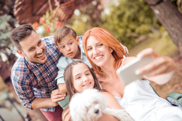 Smiling young family taking selfie in the park.