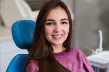 Beautiful girl with braces smiles in dentistry.