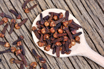 Cloves in a wooden spoon on rustic table