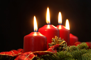 Red candles of an Advent wreath with fir branches