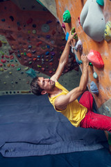 A rock climber is in a bouldering hall.